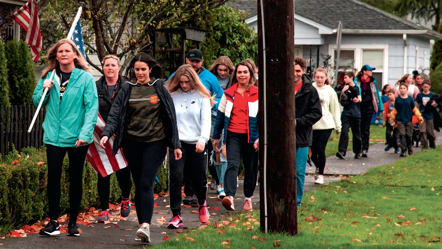 Christina Witchey carries an American Flag while walking with a group through Chehalis as part of a Wounded Warrior 5K to honor those who have served on Veterans Day
